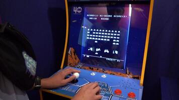 Space invaders Taito game machine. Simple Space Arcade in 8-bit retro video old game. Boy plays. Warsaw, Poland - July 28, 2023.