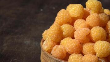 Yellow raspberries in a wooden bowl on the table. Summer berry. Vitamin food, berry harvest. Healthy nutrition video