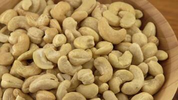 cashewnoten in een houten schaal. noten zijn gezond voedsel. houten achtergrond. cachou kern. video