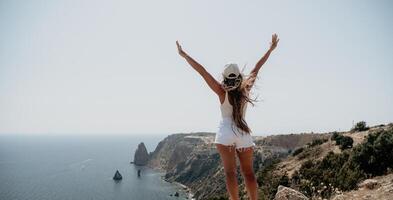 Woman summer travel sea. Happy tourist enjoy taking picture outdoors for memories. Woman traveler posing over sea bay surrounded by volcanic mountains, sharing travel adventure journey photo