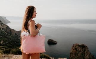 Woman travel sea. Happy tourist taking picture outdoors for memories. Woman traveler looks at the edge of the cliff on the sea bay of mountains, sharing travel adventure journey photo