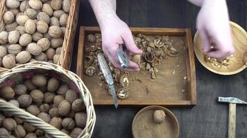 Male hands clean nuts with a nut cracker. Close-up. Walnut in shell top view. video