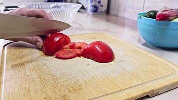 Caucasian hands cutting red tomato on bamboo cutting board at domestic kitchen, wide angle close-up with slow motion. video