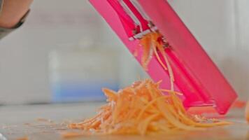 woman hands grates carrots on red grate at kitchen table video