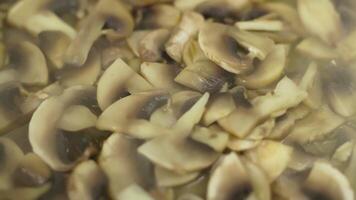 fresh champignon mushrooms frying in a frying pan, slow motion closeup video