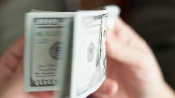 Caucasian hands holding and checking a stack of hundred us dollar banknotes video