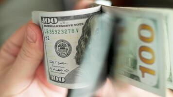 Caucasian hands holding and checking a stack of hundred us dollar banknotes video