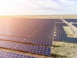 Aerial top view of a solar panels power plant. Photovoltaic solar panels at sunrise and sunset in countryside from above. Modern technology, climate care, earth saving, renewable energy concept. photo