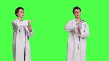 Woman physician doing timeout gesture against greenscreen backdrop, asking for a work break after multiple examinations. Doctor showing pause or stop symbol, feeling tired. Camera B. video