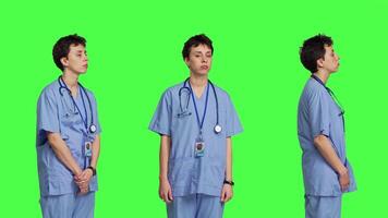 Displeased nurse saying no and sighing against greenscreen backdrop, acting disappointed while she wears blue scrubs. Medical assistant with expertise shows negative gesture, being tired. Camera B. video