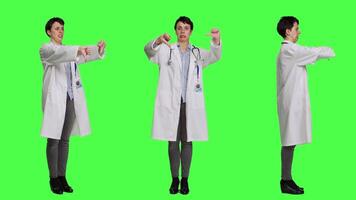 Displeased physician showing thumbs down symbol against greenscreen backdrop, expresses negativity and rejection. Doctor feeling dissatisfied and disagreeing with an idea, dislike sign. Camera A. video