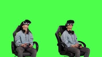 Woman playing video games using virtual reality headset in studio, enjoying cyberspace 3d gaming tournament against greenscreen backdrop. Gamer having fun with vr glasses. Camera B.