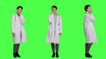 Tired general practitioner yawning and feeling overworked after night shift at hospital, exhaustion and work pressure. Medic being tired and experiencing burnout against greenscreen. Camera A. video