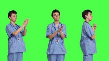 leende medicinsk assistent applåderar någon i studio, fira Framgång och glädjande mot grönskärm bakgrund. ung sjuksköterska applåder händer och känsla Lycklig handla om prestation. kamera b. video