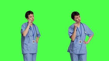 medicinsk assistent tänkande handla om ny behandling idéer i studio, verkande omtänksam medan hon står mot grönskärm bakgrund. fundersam ung sjuksköterska väger handla om sjukvård idéer. kamera b. video