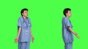 Medical assistant shrugging and doing i dont know sign in studio, acting clueless and uncertain against greenscreen backdrop. Nurse in scrubs gesticulating doubtful reaction, unsure girl. Camera B. video