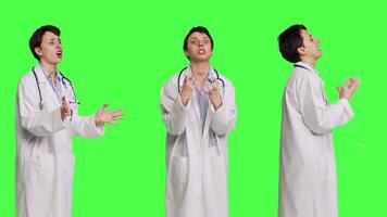 Angry physician yelling at people and being aggressive in studio, getting mad and furious at something against greenscreen backdrop. Irritated annoyed medic screaming, being displeased. Camera B. video