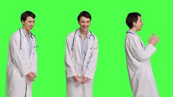 Portrait of general practitioner laughing at something against greenscreen backdrop, feeling joyful and confident with her healthcare expertise. Woman medic in white coat smiling in studio. Camera B. video