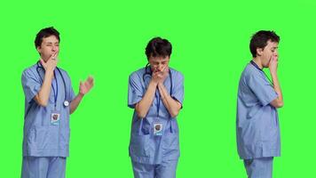 Medical assistant feeling extremely sleepy against greenscreen backdrop, being overworked after the night shift. Woman nurse yawns and feels exhausted in studio, burnout and anxiety. Camera B. video