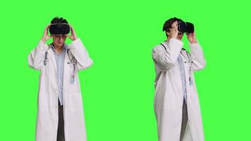 Physician uses virtual reality interactive lens on headset in studio, checks diagnosis with artificial intelligence three dimensional tool. Doctor works with vr glasses against greenscreen. Camera B. video