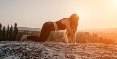 aptitud mujer. contento de edad mediana aptitud mujer haciendo extensión y pilates en un rock cerca bosque a puesta de sol. hembra aptitud yoga rutina. sano estilo de vida con atención en bienestar y relajación. foto