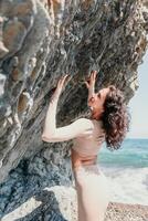 Woman travel sea. Sporty happy middle aged posing on a beach near the sea on background of volcanic rocks, like in Iceland, sharing travel adventure journey photo