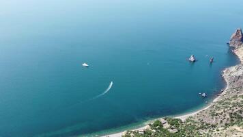 Aerial view from above on calm azure sea and volcanic rocky shores. Small waves on water surface in motion blur. Nature summer ocean sea beach background. Nobody. Holiday, vacation and travel concept video