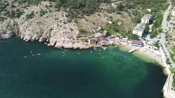 Aerial drone view on colorful kayaks grouped at a dock in sea bay. Group of happy kayakers are walking or training with instructor at sea bay. Active sea vacations concept video