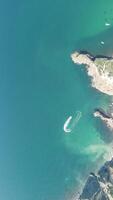 aereo Visualizza a partire dal sopra su calma azzurro mare e vulcanico roccioso sponde. piccolo onde su acqua superficie nel movimento sfocatura. natura estate oceano mare spiaggia sfondo. nessuno. vacanza, vacanza e viaggio concetto video