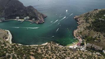 Aerial drone view on colorful kayaks grouped at a dock in sea bay. Group of happy kayakers are walking or training with instructor at sea bay. Active sea vacations concept video