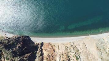 aéreo Visão a partir de acima em calma azul mar e vulcânico rochoso margens. pequeno ondas em água superfície dentro movimento borrão. natureza verão oceano mar de praia fundo. ninguém. feriado, período de férias e viagem conceito video