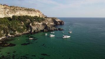 Aerial panoramic view of seascape with crystal clear azure sea and rocky shores. Yachts in a beautiful lagoon on backdrop of rocks. The concept of an ideal destination for summer travel and vacation. video