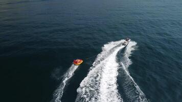 contento persone siamo andando per nuotare su un aria materasso dietro a un' Jet sciare. turisti cavalcata il gonfiabile moto d'acqua barca. mare attrazione. Jet sciare pattinando persone su un' grande gonfiabile zattera. aereo Copter Visualizza. video