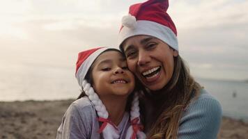 en kvinna och en barn bär santa hattar på de strand video