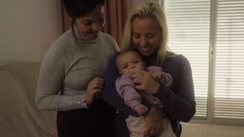 två kvinnor innehav en bebis och leende video