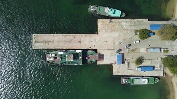 Ferry carrying cars and passengers across the sea, top down aerial drone view. Ferry on the lake, transporting cars. deck of a boat carrying vehicles. video