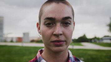 a young woman with a shaved head in a park video