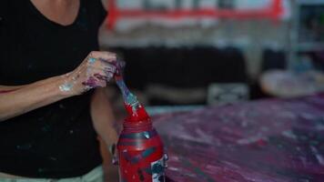 un' donna è miscelazione rosso dipingere nel un' bottiglia video