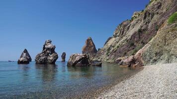 Calm azure sea and volcanic rocky shores. Small waves on water surface in motion blur. Nature summer ocean sea beach background. Nobody. Holiday, vacation and travel concept video