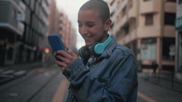 Panorama- Aussicht von rasiert Kopf Mädchen mit Handy, Mobiltelefon Smartphone während Hören Musik- mit Kopfhörer im das Stadt Straße video