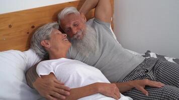 Happy senior couple smiling together in bed - Hipster mature people having funny bed time - Elderly lifestyle and love relationship concept video