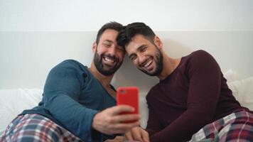 two men in pajamas taking a selfie on a bed video