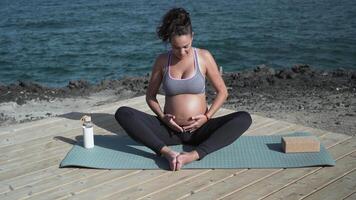 a pregnant woman is sitting on a yoga mat video