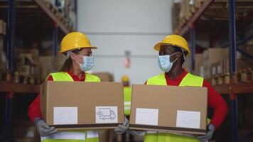 two workers in safety gear holding boxes in a warehouse video