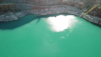 Antenne oben Aussicht auf Opencast Bergbau Steinbruch mit überflutet Unterseite, Türkis Oberfläche von das See. Steinbruch Teich bewachsen mit Grün Pflanzen und klar Türkis Wasser video