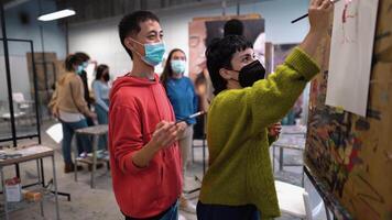 a group of people wearing masks and face coverings in an art studio video