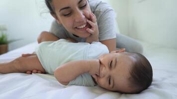 a woman smiles while laying on a bed with a baby video