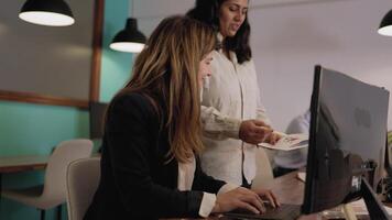 two women in an office setting looking at a computer video