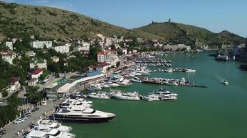 Aerial panoramic view of Balaklava landscape with boats and sea in marina bay. Crimea Sevastopol tourist attraction. Drone top view shot of port for luxury yachts, boats and sailboats. video