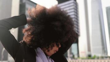 un mujer con un afro pelo estilo en frente de un ciudad video